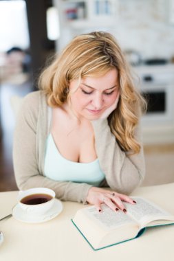 Bayan kitap okur ve kahve içer
