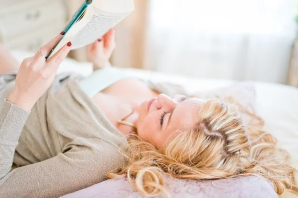 Woman reading on a bed — Stock Photo, Image