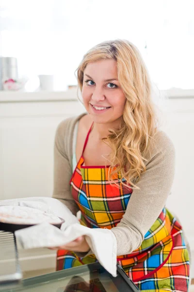 Frau zieht Kuchen aus Ofen — Stockfoto