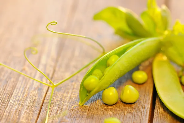 Gousses de pois frais sur une table en bois — Photo