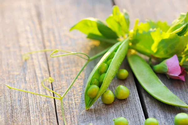 Gousses de pois frais sur une table en bois — Photo