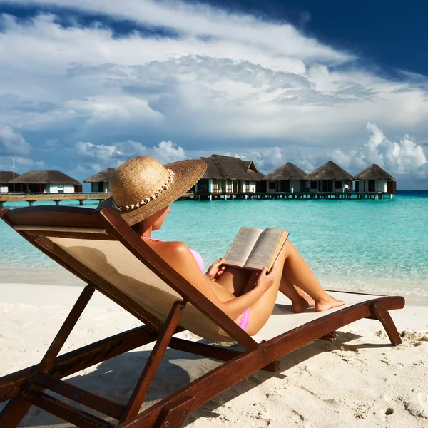 Jonge vrouw lezen van een boek op strand — Stockfoto