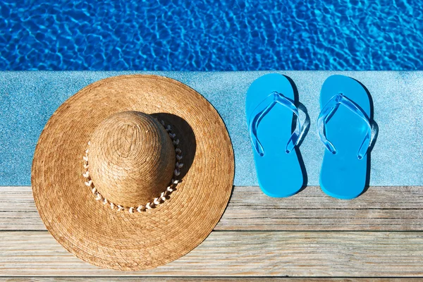 Zapatillas azules y sombrero junto a una piscina —  Fotos de Stock