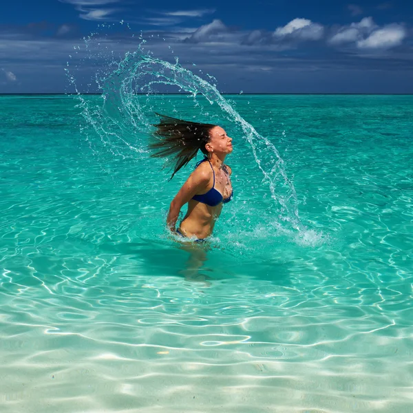 Mujer salpicando agua con pelo en el océano — Foto de Stock