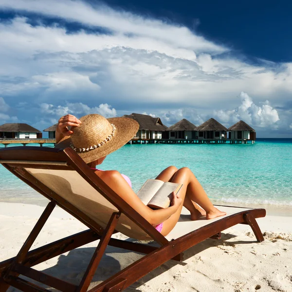 Jonge vrouw lezen van een boek op strand — Stockfoto