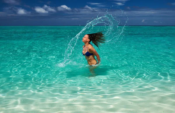 Женщина брызгает водой с волосами в океане — стоковое фото