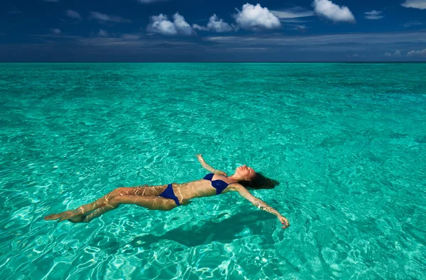 Donna in bikini sdraiata sull'acqua — Foto Stock