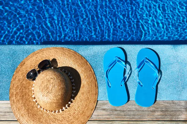 Blue slippers and hat by a swimming pool Stock Photo