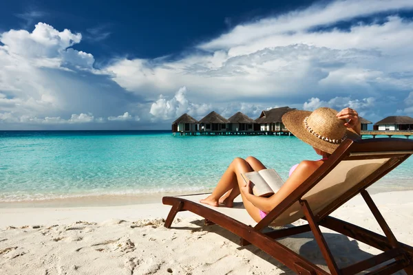 Giovane donna che legge un libro in spiaggia — Foto Stock