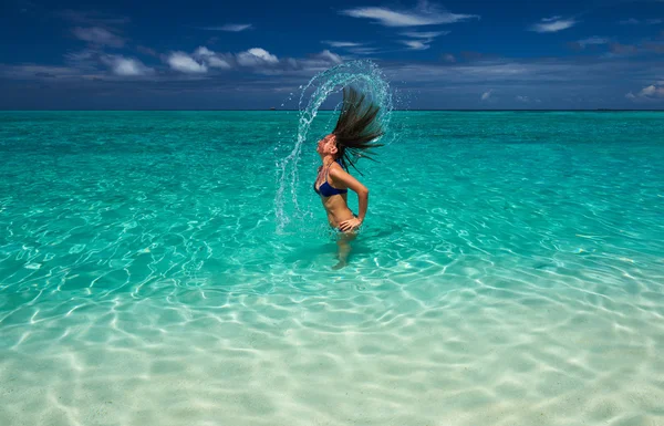 Mujer salpicando agua con pelo en el océano — Foto de Stock