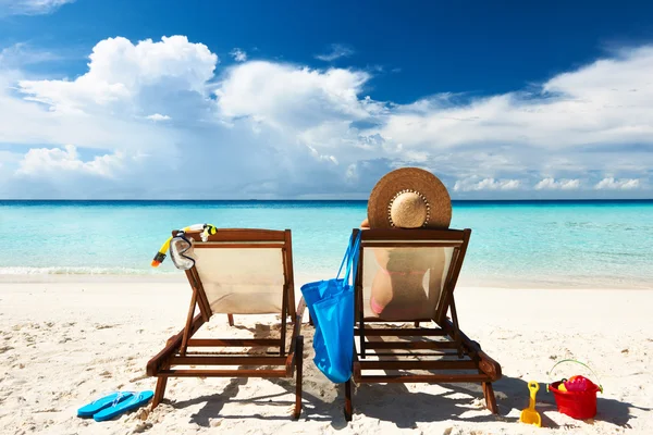 Vrouw op een tropisch strand in chaise lounge — Stockfoto