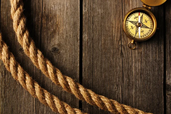 Starožitný kompas a lana přes dřevěné pozadí — Stock fotografie