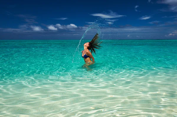 Mujer salpicando agua con pelo en el océano — Foto de Stock