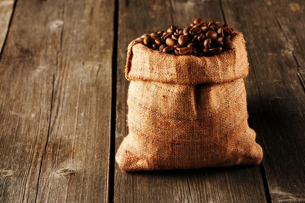 Granos de café en bolsa en la mesa —  Fotos de Stock