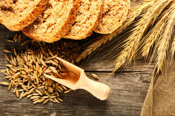 Rozs spikelets és szeletelt kenyér, fából készült háttér — Stock Fotó