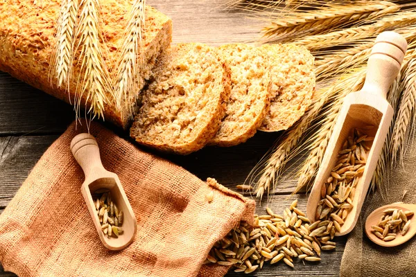 Rozs spikelets és szeletelt kenyér, fából készült háttér — Stock Fotó