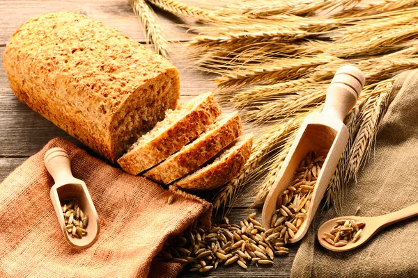 Ржаные шипы и нарезанный хлеб на деревянном фоне — стоковое фото