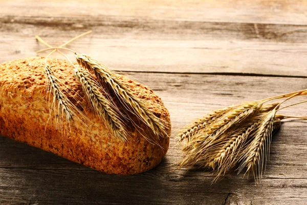 Rozs spikelets és a kenyér, a fából készült háttér — Stock Fotó