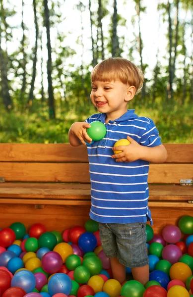 Bambino felice che gioca con palline di plastica colorate — Foto Stock