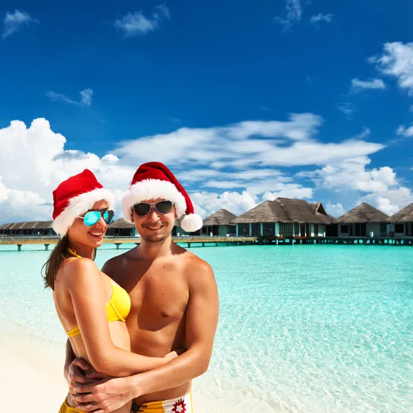 在圣诞老人的帽子在马尔代夫的海滩上的情侣 — 图库照片