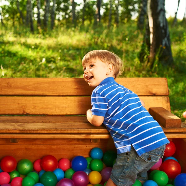 Happy child playing with colorful plastic balls — Stock Photo, Image