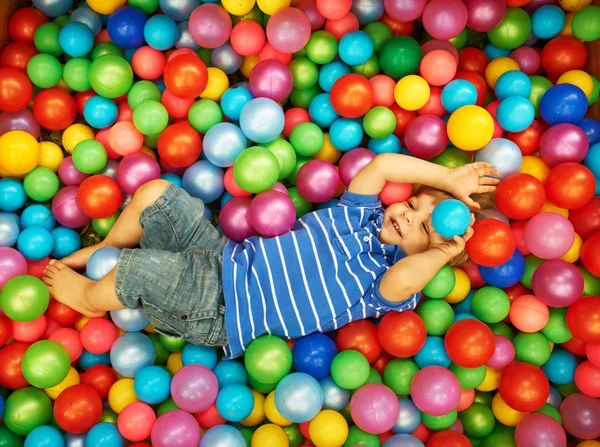 Šťastné dítě hraje s barevné plastové míčky — Stock fotografie