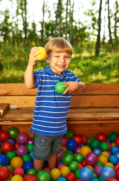 Bambino felice che gioca con palline di plastica colorate — Foto Stock