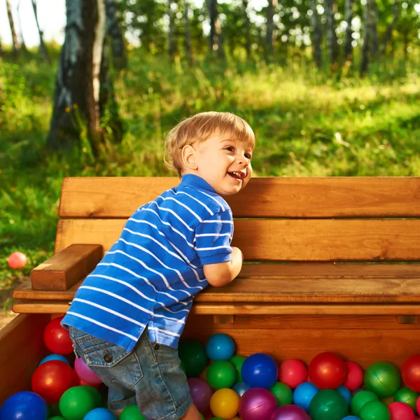 Copil fericit jucându-se cu bile de plastic colorate — Fotografie, imagine de stoc