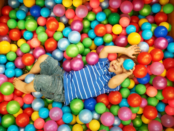 Niño feliz jugando con bolas de plástico de colores —  Fotos de Stock