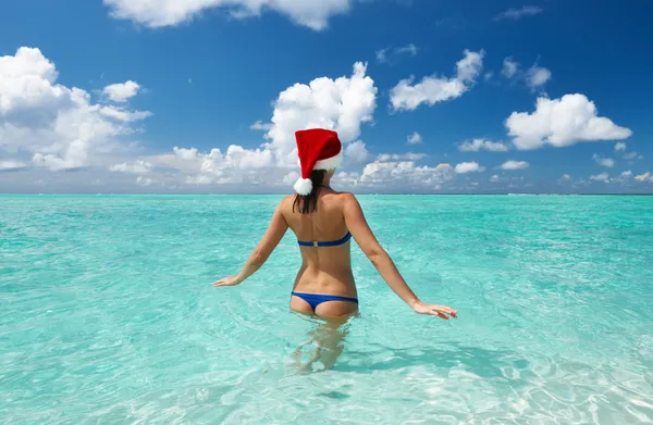 Frau mit Weihnachtsmütze am Strand — Stockfoto