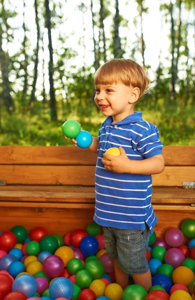 Criança feliz brincando com bolas plásticas coloridas — Fotografia de Stock