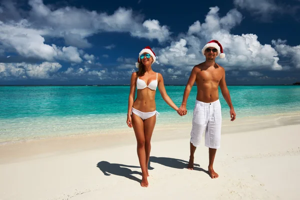 Casal no chapéu do Papai Noel em uma praia — Fotografia de Stock