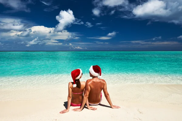 Casal no chapéu do Papai Noel em uma praia — Fotografia de Stock