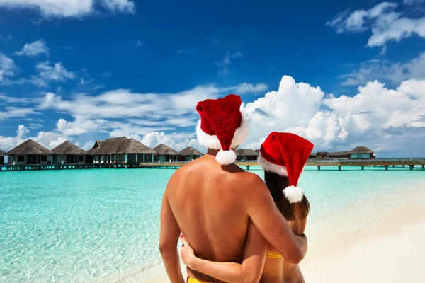 Couple dans le chapeau du Père Noël sur une plage — Photo