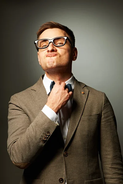 Confident nerd in eyeglasses adjusting his bow-tie — Stock Photo, Image