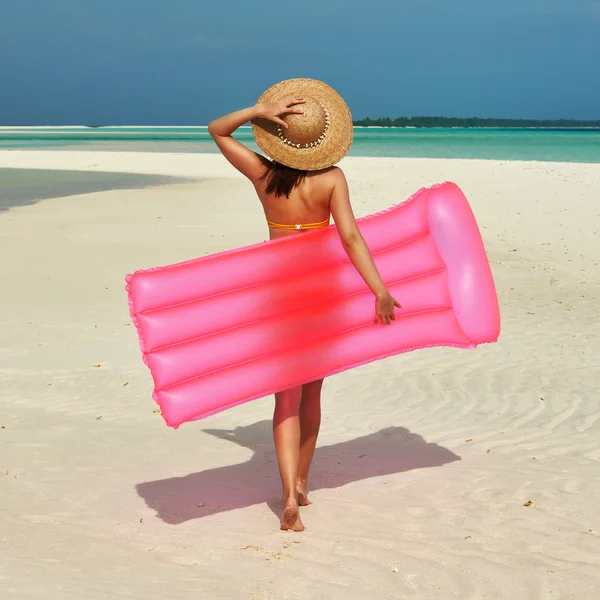 Женщина с розовым надувным плотом на пляже — стоковое фото