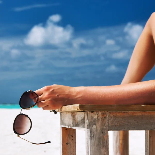 Femme à la plage tenant des lunettes de soleil — Photo