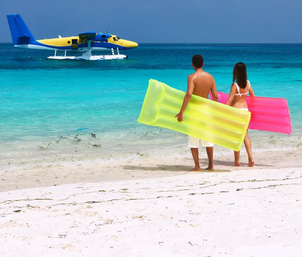 Casal com jangadas infláveis olhando para o hidroavião na praia — Fotografia de Stock