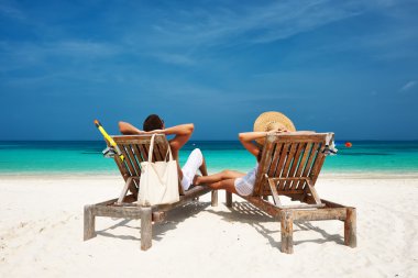 Couple in white relax on a beach at Maldives clipart