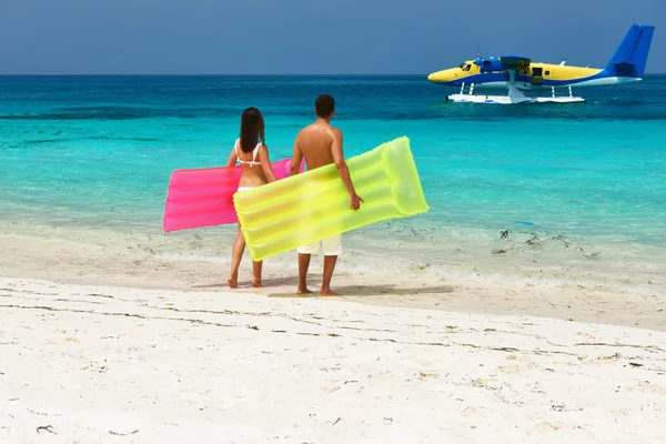 夫妇与充气筏看着水上飞机在海滩上 — 图库照片
