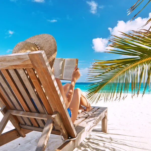 Ung kvinna läser en bok på stranden — Stockfoto