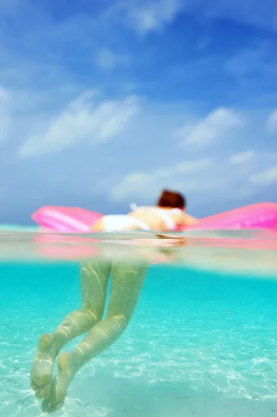 Жінка розслабляється на надувному матраці, вид з-під води — стокове фото