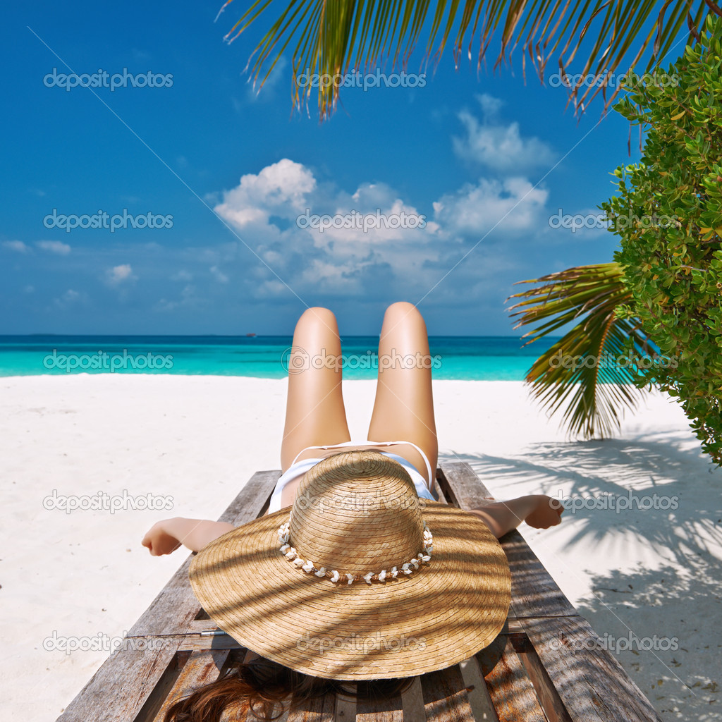 Woman at beach lying on chaise lounge
