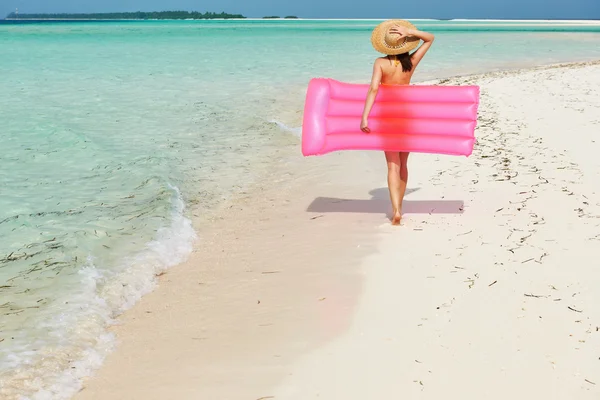 Nő, rózsaszín felfújható tutaj a strandon — Stock Fotó