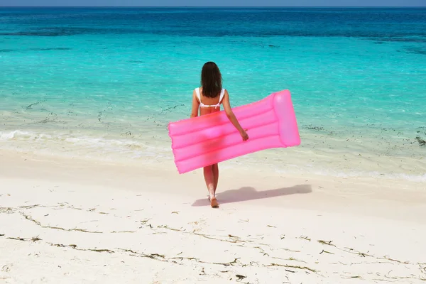 Kobieta z różowym nadmuchiwane tratwa na plaży — Zdjęcie stockowe