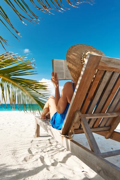 Молода жінка читає книгу на пляжі — стокове фото