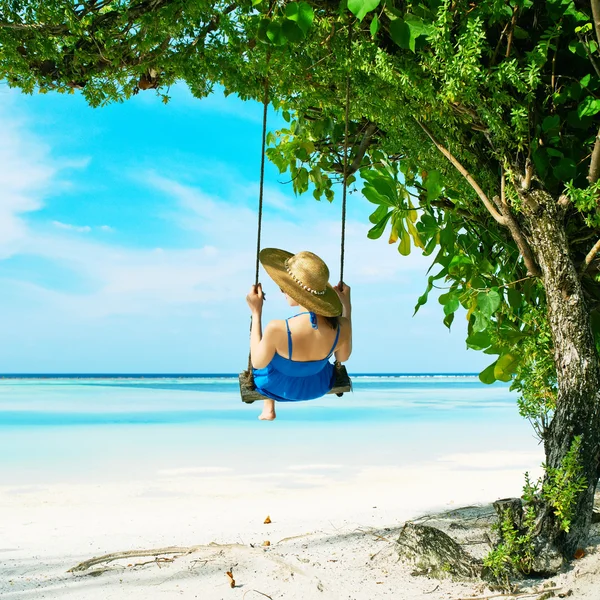 Kvinna i blå klänning swinging på stranden — Stockfoto