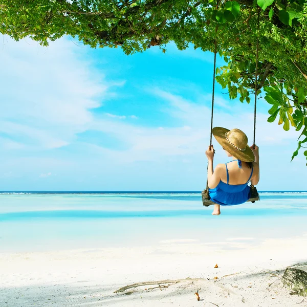 Kvinna i blå klänning swinging på stranden — Stockfoto