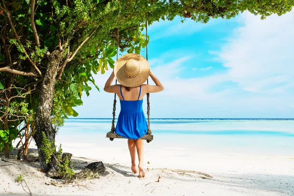 Kvinna i blå klänning swinging på stranden — Stockfoto