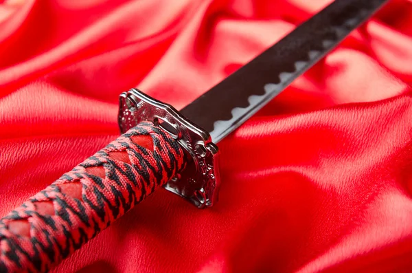 Japanese sword takana on red satin background — Stock Photo, Image